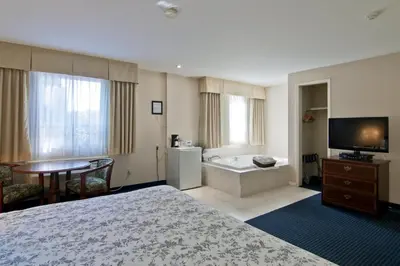 a hotel room with a bed and a television and a tub at Travelodge by Wyndham Trenton in Trenton