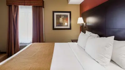 a hotel room with a large bed with white pillows at Best Western Plus Bowmanville in Bowmanville