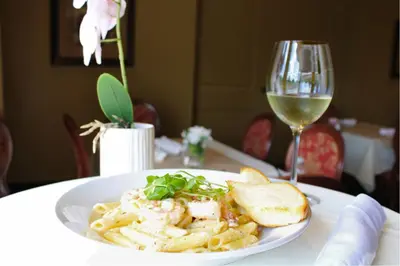 a plate of pasta with bread and a glass of wine at Monte Carlo Inn & Suites Downtown Markham in Markham