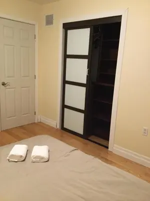 two white towels sitting on a bed in front of a door at Dairy Homestay in Toronto