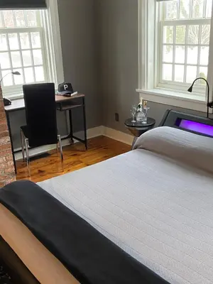 a bedroom with a bed and a desk and windows at Old Ivy Walk in Niagara on the Lake