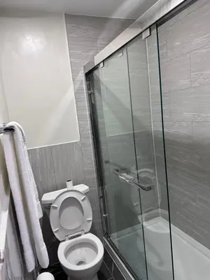 a bathroom with a toilet and a glass shower at Cedar Springs Motel in Acton