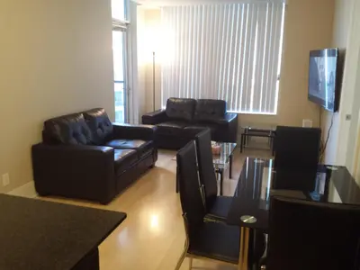 a living room with black leather furniture and a television at BEST LOCATION/SPECTACULAR VIEW 2 BEDROOMS FURNISHED CONDO S/L RENT in Mississauga