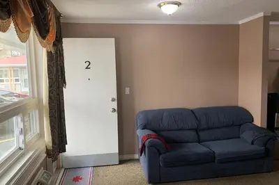 a living room with a blue couch and a door at Lucien Motel in Whitby