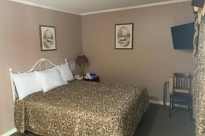 a hotel room with a bed and a chair at Lucien Motel in Whitby