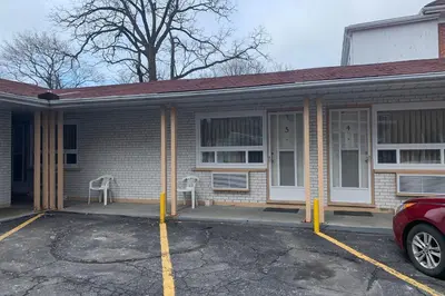 a house with a car parked in a parking lot at Lucien Motel in Whitby