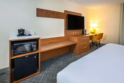 a hotel room with a bed and a desk with a tv at Comfort Inn & Suites in Ingersoll