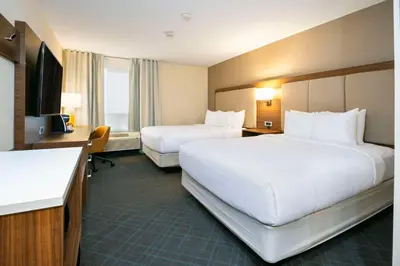 a hotel room with two beds and a desk at Comfort Inn & Suites in Ingersoll
