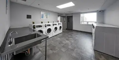 a laundry room with two washing machines and a sink at Residence & Conference Centre - King City in King City