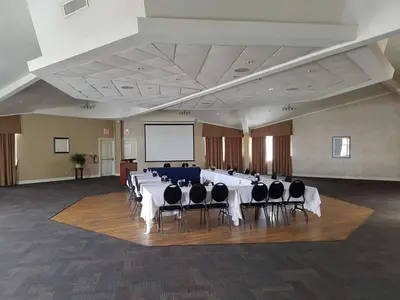 a conference room with a table and chairs and a screen at Best Western Plus Durham Hotel & Conference Centre in Oshawa