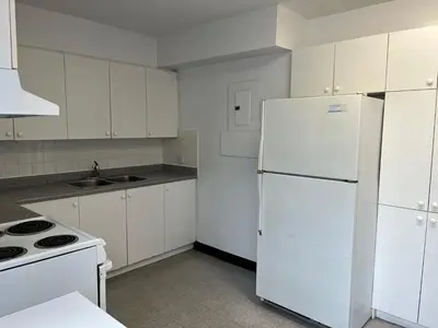 a kitchen with white cabinets and a white refrigerator at Neill Wycik Hostel in Toronto