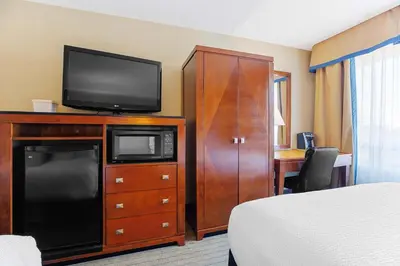 a hotel room with a bed and a television on a cabinet at Sandman Hotel & Suites London Downtown in London