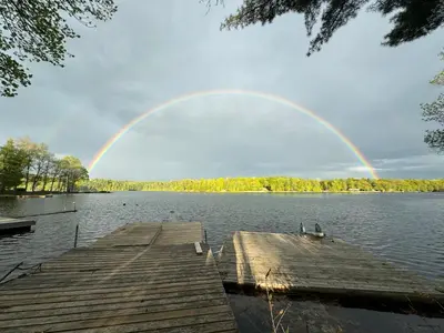 a rainbow over a lake with a wooden dock at Noble Motel in Norland