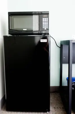 a microwave sitting on top of a black refrigerator at United College in Waterloo