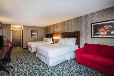 a hotel room with two beds and a red couch at Ramada by Wyndham Jackson's Point in Georgina