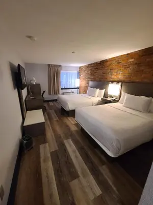 a hotel room with two beds and a brick wall at Travelodge by Wyndham Barrie in Barrie