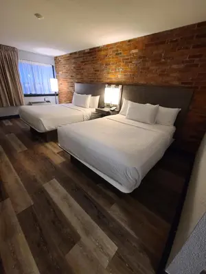 a hotel room with two beds and a brick wall at Travelodge by Wyndham Barrie in Barrie