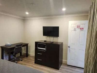 a room with a bed and a desk and a television at Fairway Inn & Suites in Kitchener