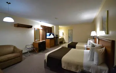 a hotel room with two beds and a couch and a television at Newmarket Inn in Newmarket