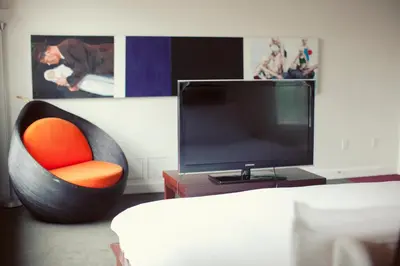 a living room with a tv and a chair at Hotel Ocho in Toronto