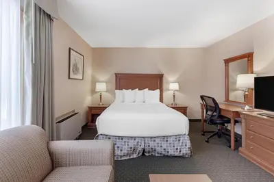 a hotel room with a bed and a desk and chairs at Best Western Plus Otonabee Inn in Peterborough