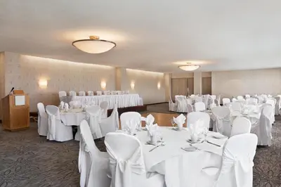 a banquet room with white tables and chairs at Ramada by Wyndham Belleville Harbourview Conference Center in Belleville