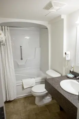 a white bathroom with a toilet and a sink at The Village Inn of Lakefield in Lakefield