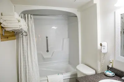 a white bathroom with a shower and a toilet at The Village Inn of Lakefield in Lakefield