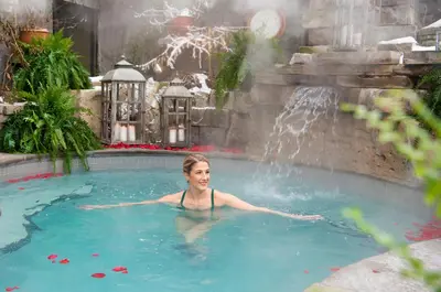a woman in a swimming pool with a waterfall at Pillar and Post Inn & Spa in Niagara on the Lake