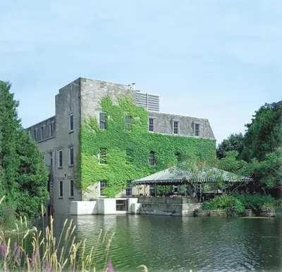 a building with green ivy on it next to a body of water at Millcroft Inn & Spa in Alton