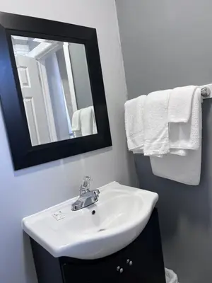 a bathroom with a sink and a mirror and towels at Knights Inn - Park Villa Motel, Midland in Midland