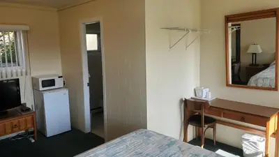a hotel room with a bed and a desk and a mirror at Wasaga Beach Inn And Cottages in Wasaga Beach