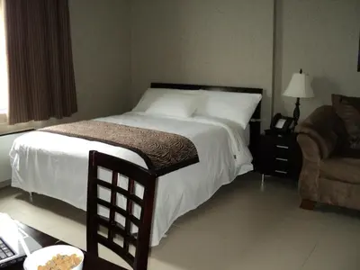 a bedroom with a large bed and a chair at Montecassino Hotel & Event Centre in Toronto