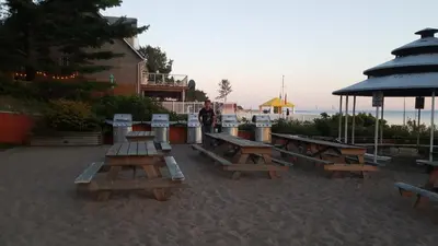 a group of wooden picnic tables on the beach at SunPort Beach Resort in Balm Beach