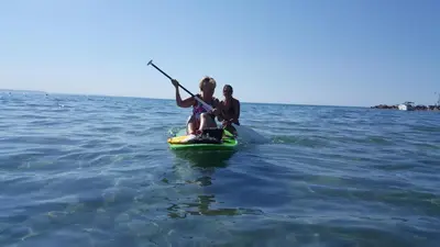 two people are sitting on a paddle board in the water at SunPort Beach Resort in Balm Beach