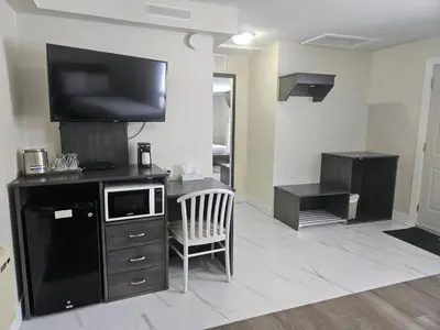 a living room with a tv and a desk with a chair at Leelas Villa Inn Flesherton in Flesherton