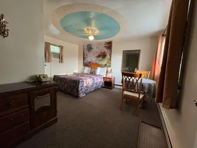 a bedroom with a bed and a table and a chair at Holiday Motel in Orillia