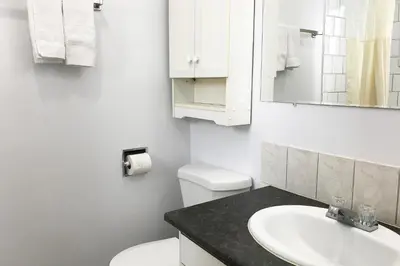 a white bathroom with a toilet and a sink at Bayside Motel Trenton in Trenton