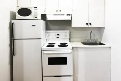 a white kitchen with a stove and a refrigerator at Bayside Motel Trenton in Trenton