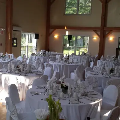 a room filled with white tables and chairs with white table linens at Timber House Resort in Brighton