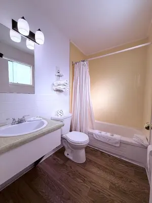 a bathroom with a toilet and a sink and a tub at Guest Inn Motel in Trenton