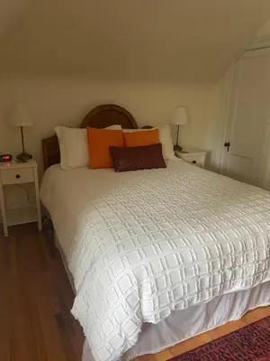 a bedroom with a large white bed with orange pillows at Cottage on Caledonia Bed & Breakfast in Stratford