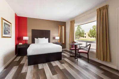 a hotel room with a bed and a table and a window at Travelodge by Wyndham Lindsay in Lindsay