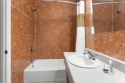 a bathroom with a sink and a shower and a tub at Travelodge by Wyndham Lindsay in Lindsay