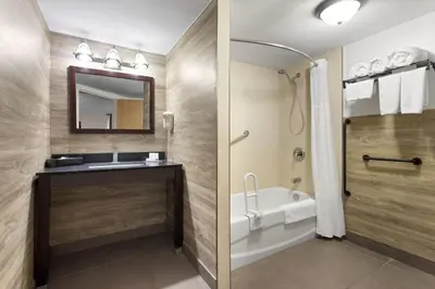 a bathroom with a tub and a sink and a mirror at Travelodge by Wyndham Lindsay in Lindsay