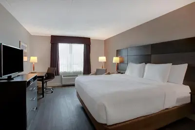 a hotel room with a bed and a flat screen tv at Days Inn & Suites by Wyndham Collingwood in Collingwood