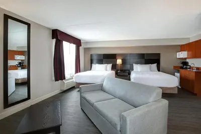 a hotel room with two beds and a couch at Days Inn & Suites by Wyndham Collingwood in Collingwood