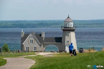 a man and two children walking past a lighthouse at The Inn at Cobble Beach in Kemble