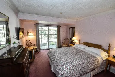 a bedroom with a bed and a dresser and windows at Blairpen House Country Inn in Niagara on the Lake