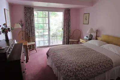 a hotel room with a large bed and a balcony at Blairpen House Country Inn in Niagara on the Lake